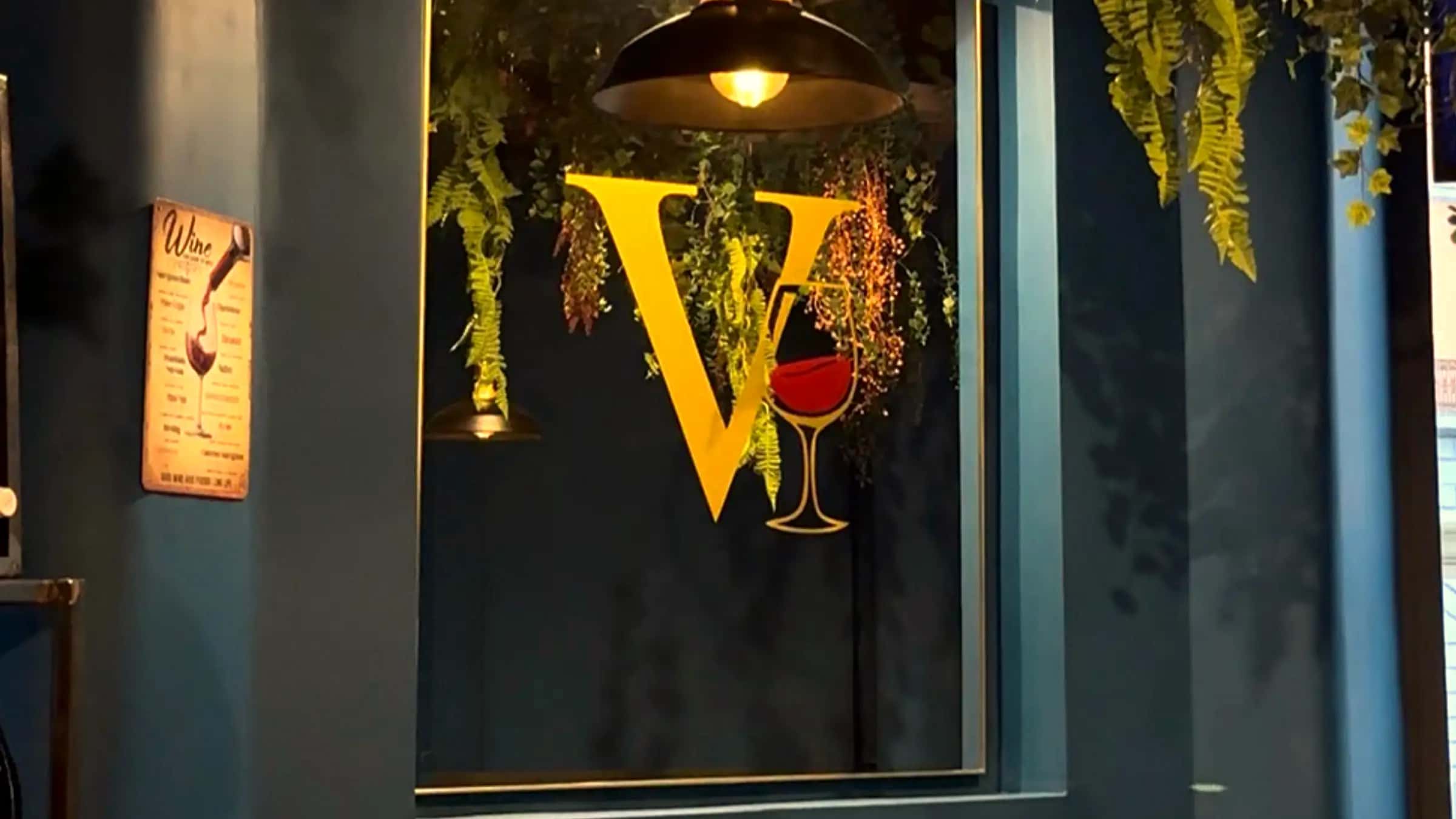 Il logo V dorato di VinCarne by Dixie, illuminato tra il verde sospeso in sala