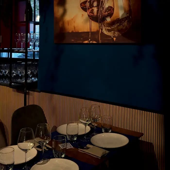 Un angolo di VinCarne by Dixie: quadro d'autore sul vino, cantinetta e tavolo apparecchiato